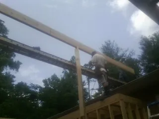 Carpenter setting a ridge beam over a new addition frame — Ice Dam Removal by Roofing Brothers in Gloversville