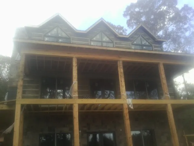 Dormers and porch framing on a large log home under construction — Roof Coating work by our crew in Gloversville