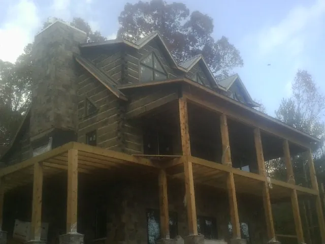 Stone chimney and dormers on a large log home with a timber porch in Gloversville