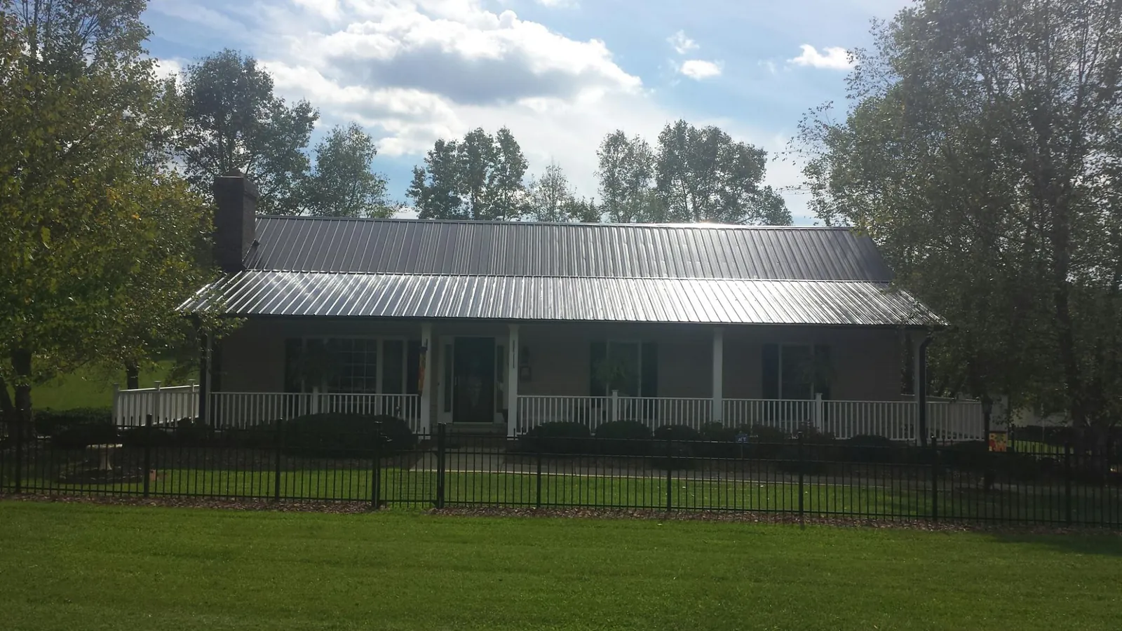 Gray metal roof on a brick ranch with a full width front porch — Gutter Guard Installation work by our crew in Gloversville