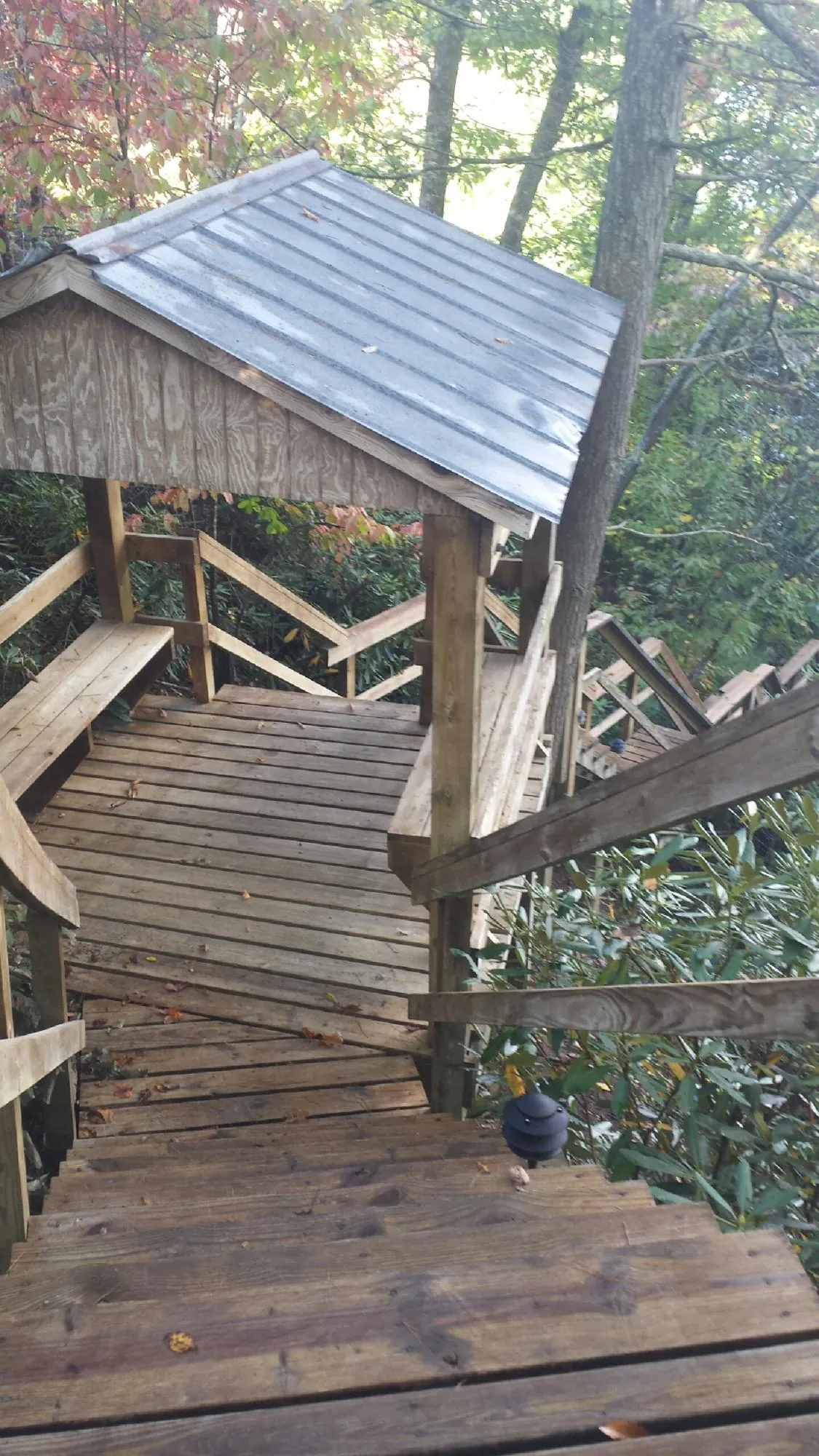 Metal roofed shelter over wooden steps on a wooded walkway — Skylight Repair & Installation work by our crew in Gloversville