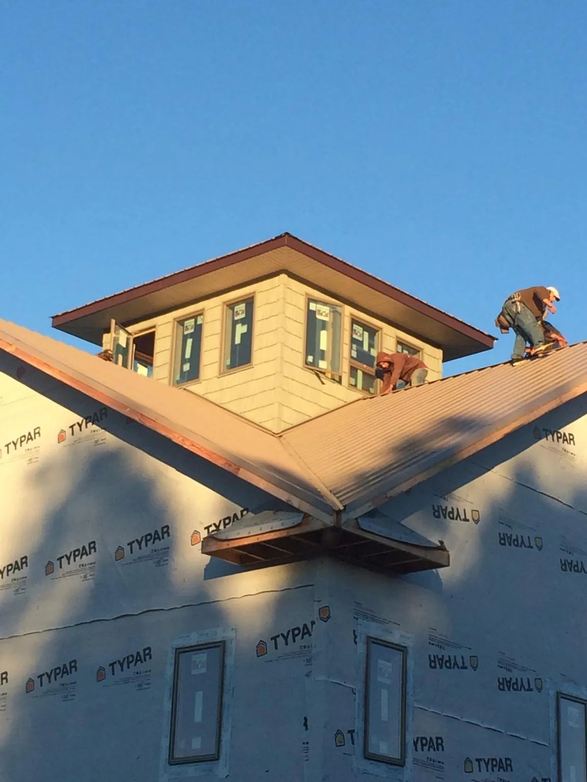 Roofers working around a rooftop cupola on a new metal roof at sunset — Roof Waterproofing in Gloversville by Roofing Brothers